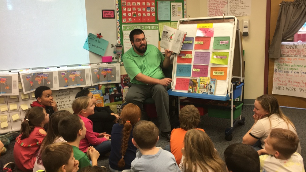Mr. Devon Fogarty animatedly reads "The Grinch" to third graders
