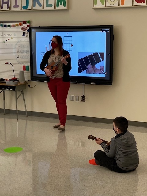 Ms. Hastings demonstrating whole, half and quarter notes on a ukulele.